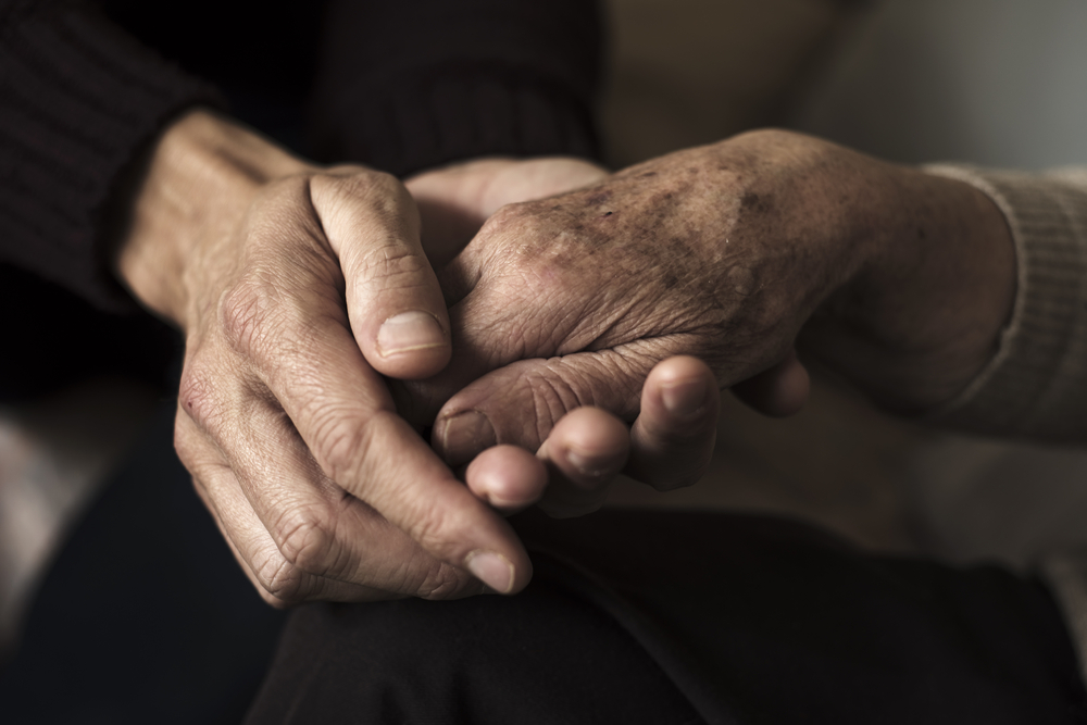 Close-up of two elderly people holding hands.